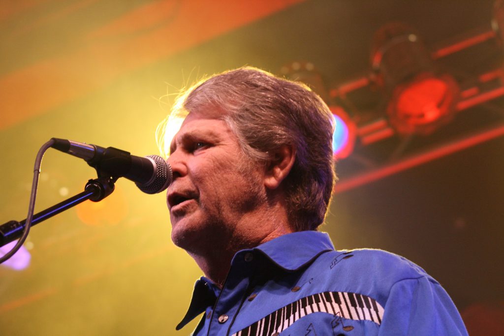 A picture of Brian Wilson from The Beach Boys, singing into a microphone.